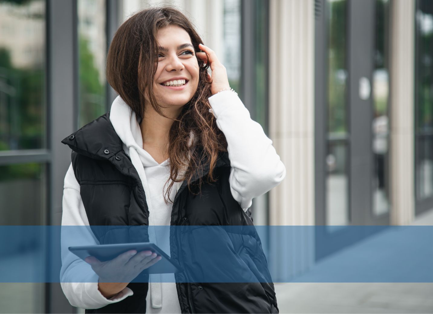 A young woman walking in the street holding an ipad, representing the salary calculator tool provided by Konnekt.